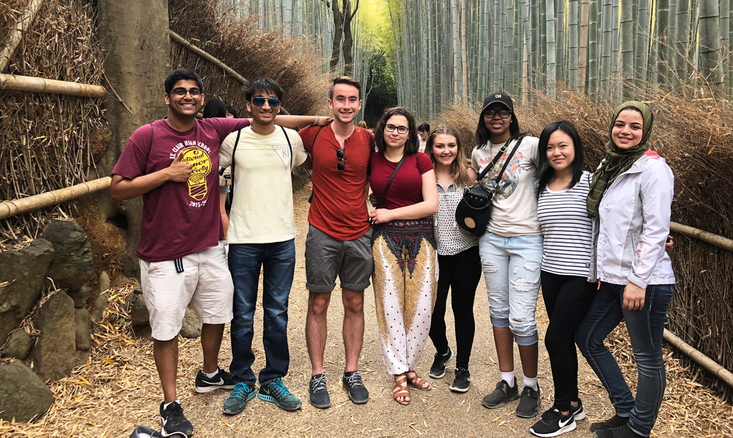A group of people standing together on a path surrounded by tall bamboo stalks and natural scenery.